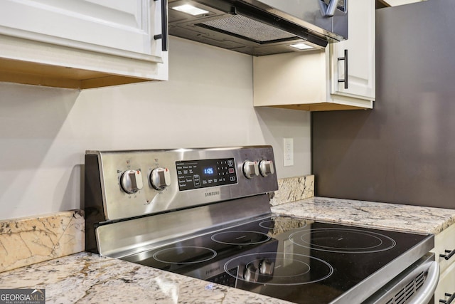 kitchen with white cabinets, light stone counters, stainless steel range with electric stovetop, and range hood