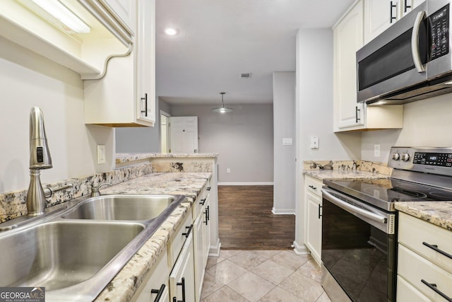 kitchen featuring white cabinetry, sink, light stone counters, appliances with stainless steel finishes, and light wood-type flooring