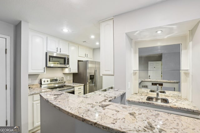 kitchen featuring kitchen peninsula, light stone counters, stainless steel appliances, sink, and white cabinets