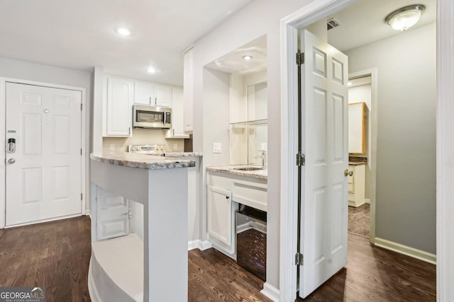 kitchen with white cabinets, appliances with stainless steel finishes, and dark hardwood / wood-style floors