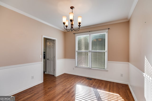 spare room featuring an inviting chandelier, ornamental molding, and dark hardwood / wood-style floors