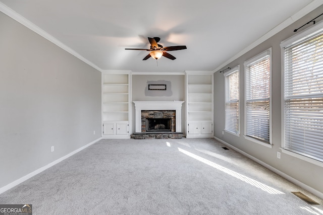 unfurnished living room with a stone fireplace, plenty of natural light, ornamental molding, and carpet