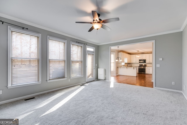 unfurnished living room featuring ornamental molding, ceiling fan, and carpet