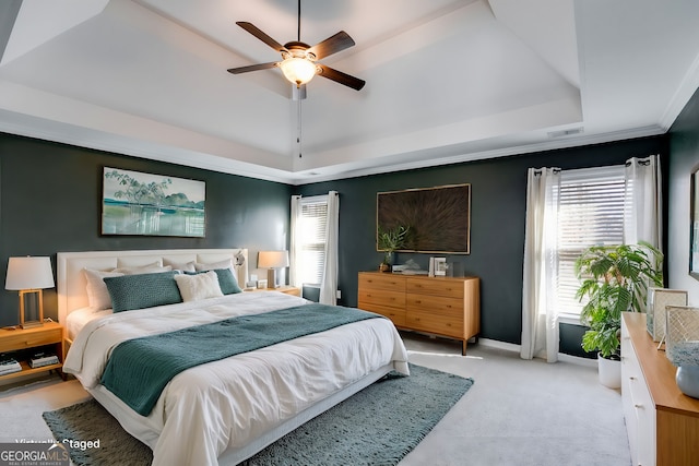 bedroom featuring a raised ceiling, crown molding, light carpet, and ceiling fan