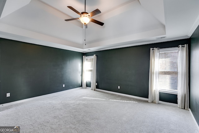 carpeted spare room featuring crown molding, a tray ceiling, and ceiling fan