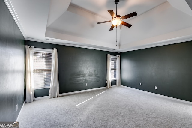 carpeted spare room with crown molding, a tray ceiling, vaulted ceiling, and ceiling fan