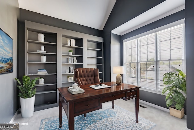 home office featuring lofted ceiling and built in shelves