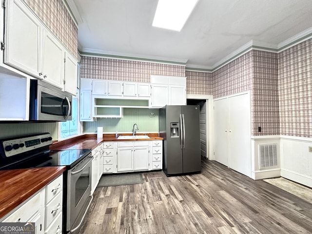 kitchen with appliances with stainless steel finishes, wooden counters, white cabinetry, sink, and ornamental molding