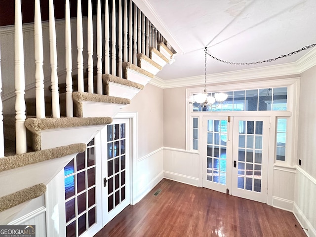 interior space with dark hardwood / wood-style flooring, a notable chandelier, ornamental molding, and french doors