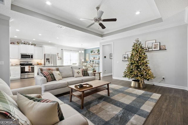 living room with a textured ceiling, dark hardwood / wood-style floors, a raised ceiling, and crown molding