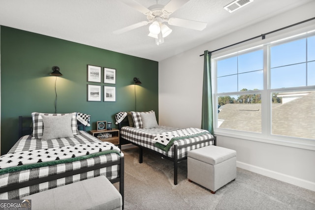 bedroom featuring ceiling fan, light carpet, and a textured ceiling