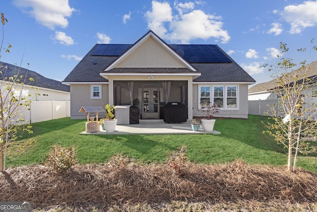 rear view of property featuring solar panels and a yard