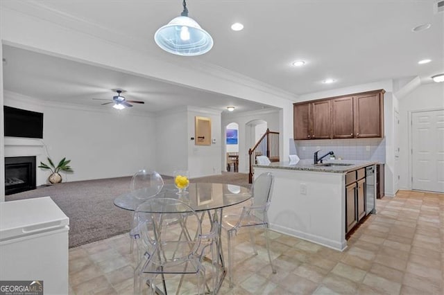 kitchen featuring pendant lighting, crown molding, sink, decorative backsplash, and ceiling fan