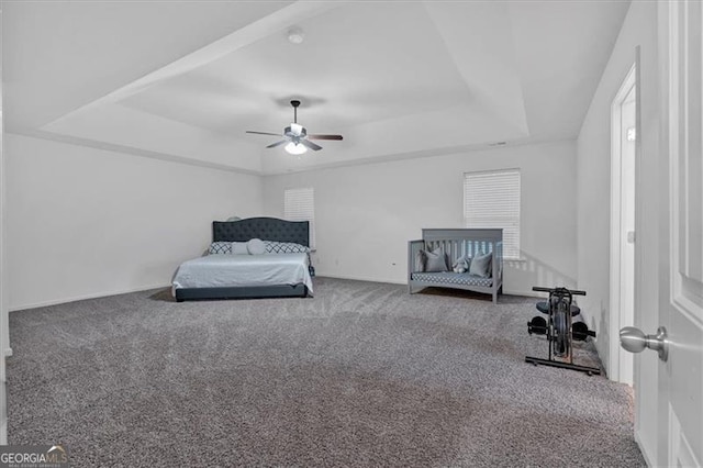 carpeted bedroom featuring a raised ceiling and ceiling fan