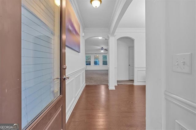 corridor featuring dark hardwood / wood-style flooring, ornate columns, and ornamental molding