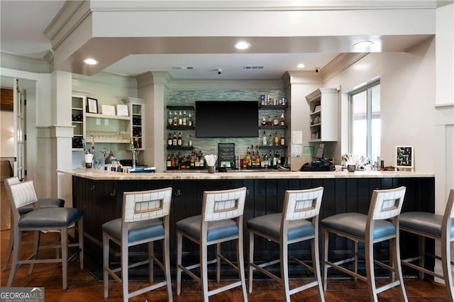 bar with dark wood-type flooring and crown molding