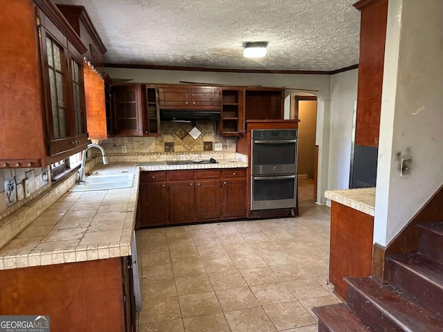 kitchen featuring decorative backsplash, black electric stovetop, double oven, crown molding, and sink