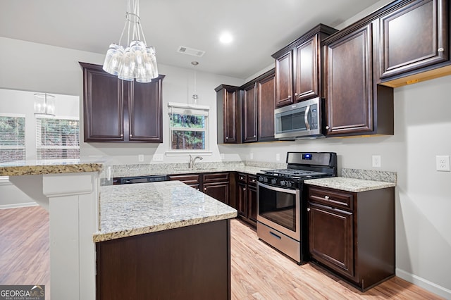 kitchen with stainless steel appliances, sink, pendant lighting, light hardwood / wood-style flooring, and a chandelier