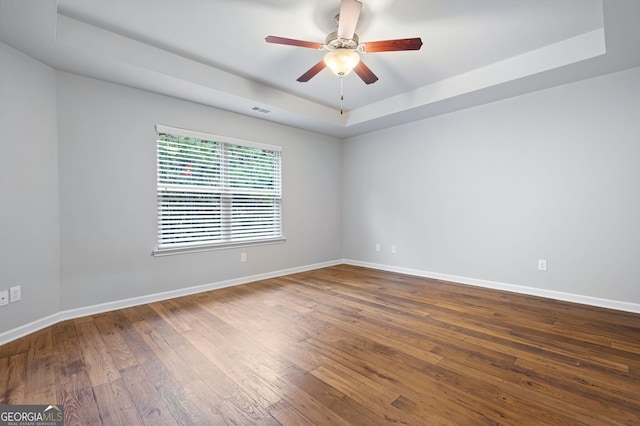 empty room featuring hardwood / wood-style floors, a tray ceiling, and ceiling fan