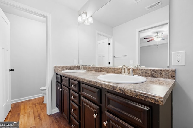 bathroom with wood-type flooring, vanity, toilet, and ceiling fan