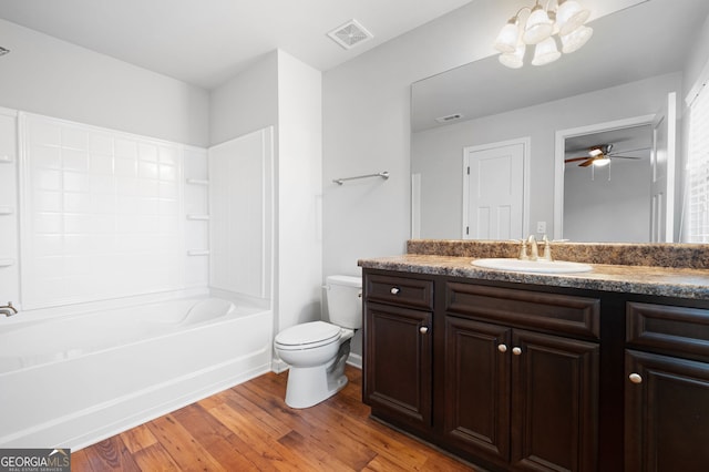 full bathroom featuring ceiling fan, washtub / shower combination, toilet, vanity, and hardwood / wood-style flooring