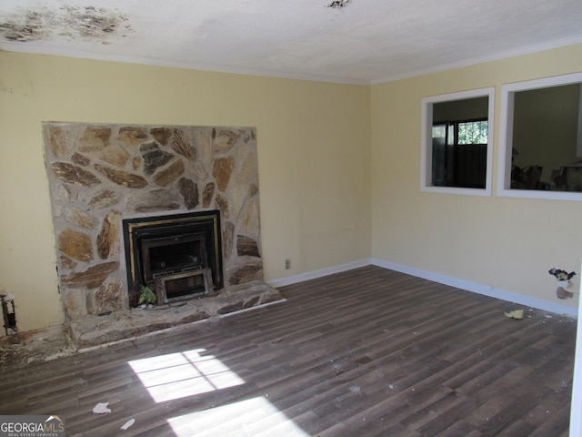 unfurnished living room with dark wood-type flooring, a textured ceiling, and ornamental molding