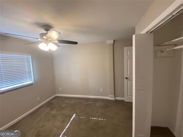 unfurnished bedroom with dark colored carpet, ceiling fan, and a closet