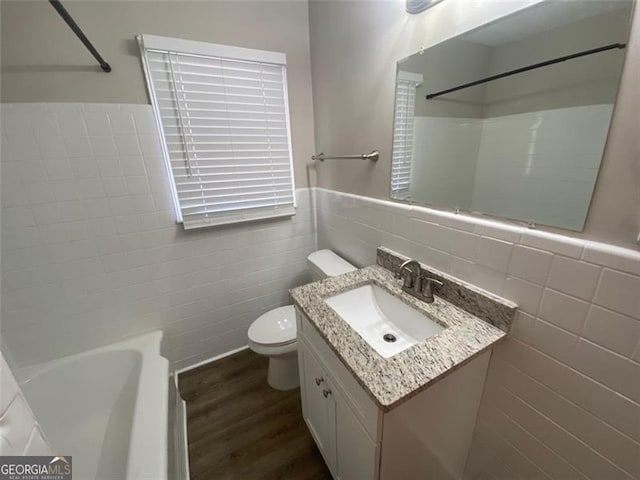 bathroom featuring vanity, hardwood / wood-style flooring, toilet, and tile walls