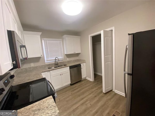 kitchen with sink, dark hardwood / wood-style floors, light stone countertops, appliances with stainless steel finishes, and white cabinetry