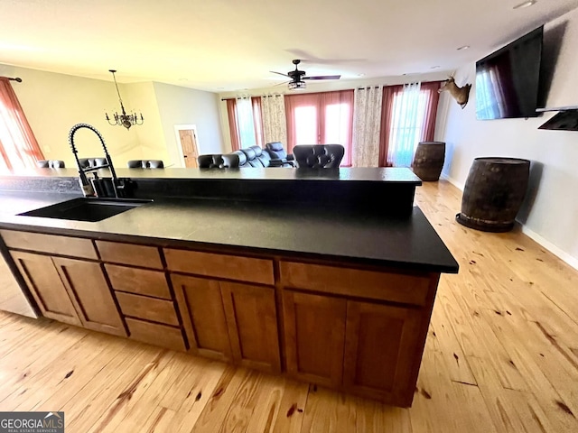 kitchen with decorative light fixtures, sink, ceiling fan with notable chandelier, and light hardwood / wood-style flooring