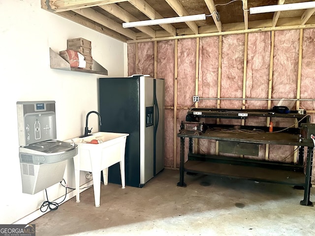 kitchen featuring stainless steel refrigerator with ice dispenser and concrete floors