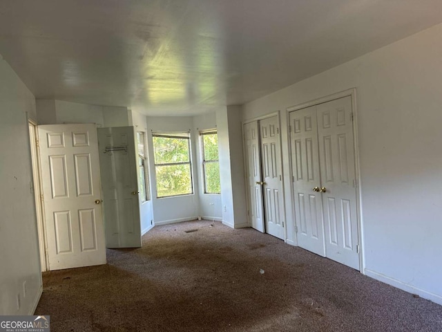 unfurnished bedroom with carpet and two closets