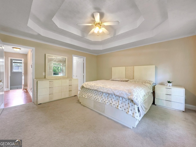 bedroom featuring a raised ceiling, ceiling fan, and light colored carpet