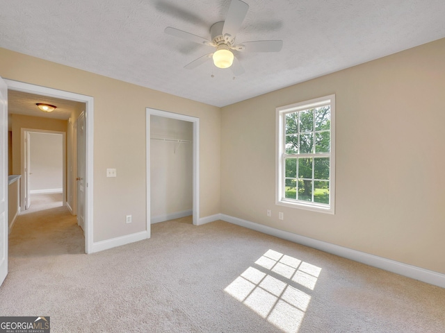 unfurnished bedroom with light carpet, a textured ceiling, a closet, and ceiling fan