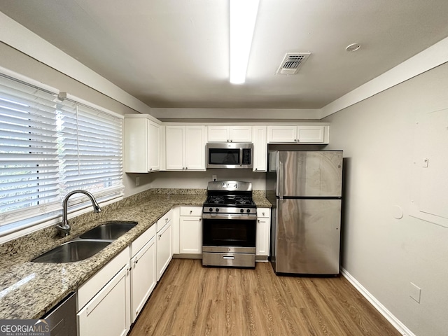 kitchen with sink, light hardwood / wood-style flooring, light stone counters, white cabinetry, and stainless steel appliances