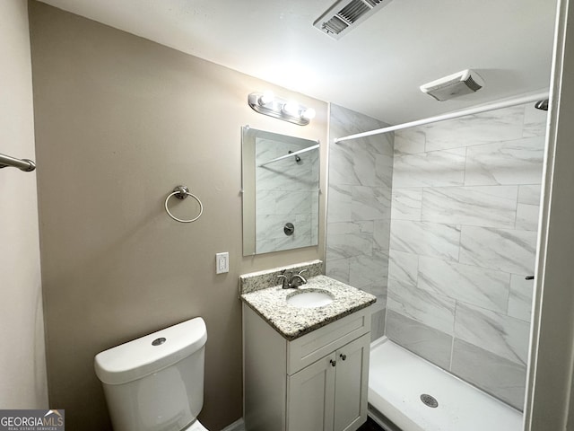 bathroom featuring vanity, toilet, and a tile shower