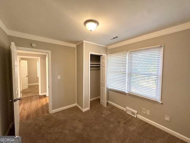 unfurnished bedroom with crown molding, a closet, and dark carpet