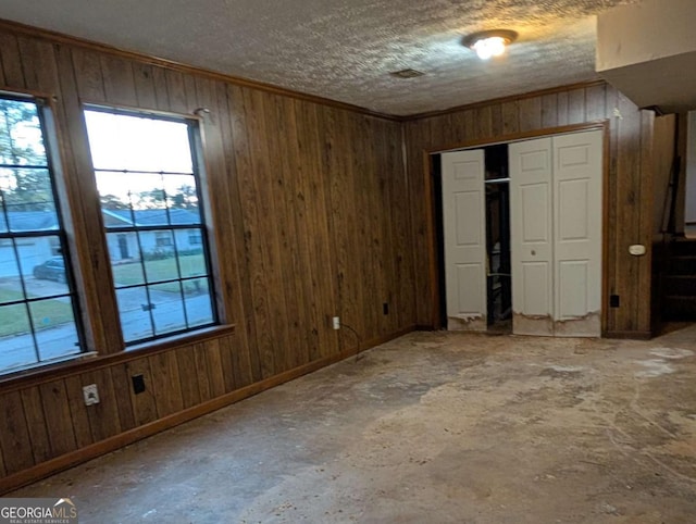 unfurnished bedroom with wood walls, a textured ceiling, and a closet