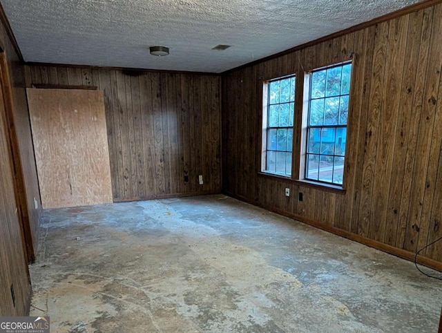 empty room with a textured ceiling and wood walls