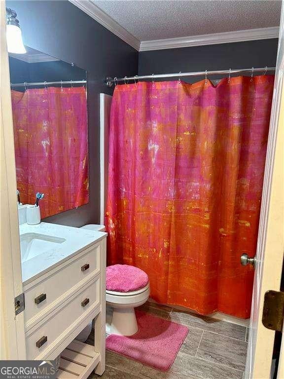 bathroom featuring vanity, toilet, ornamental molding, and a textured ceiling