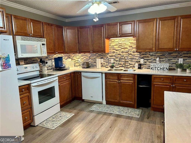 kitchen with crown molding, sink, white appliances, and light wood-type flooring