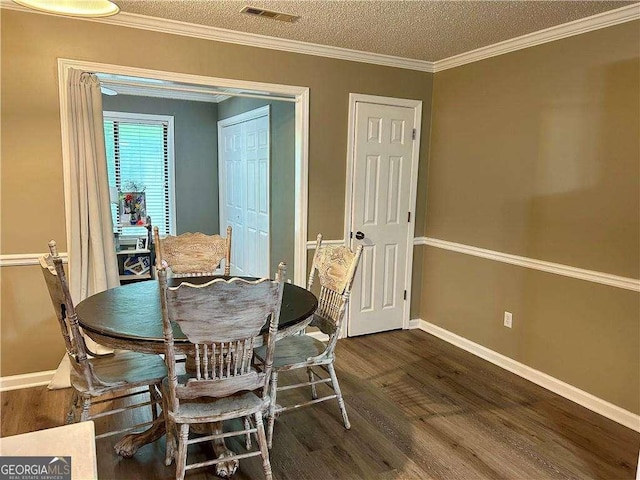 dining area with a textured ceiling, ornamental molding, and dark wood-type flooring