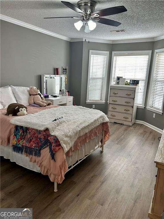 bedroom with ceiling fan, wood-type flooring, and ornamental molding