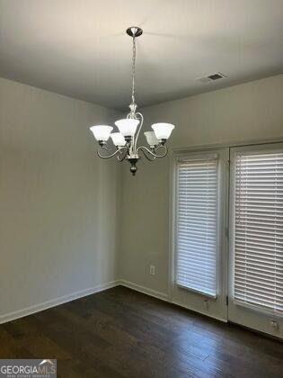 spare room featuring dark hardwood / wood-style flooring and an inviting chandelier