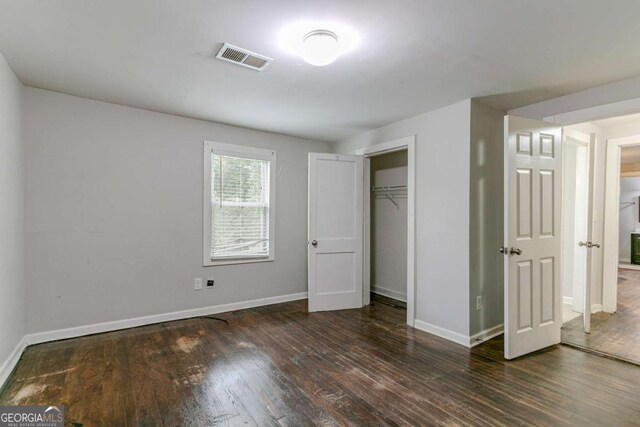 unfurnished bedroom with dark hardwood / wood-style flooring and a closet