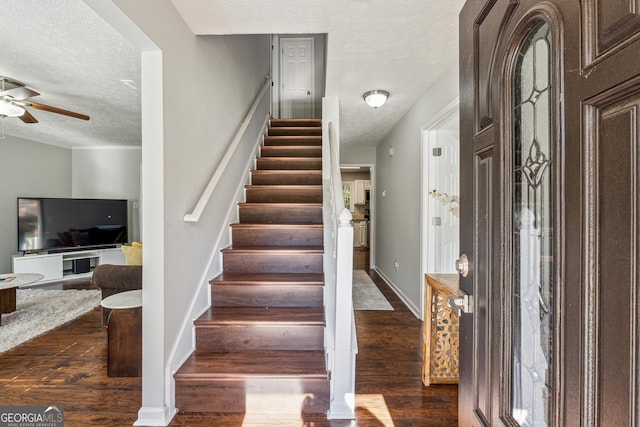 entrance foyer with a textured ceiling, ceiling fan, and dark wood-type flooring