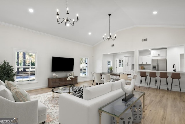 living room with light hardwood / wood-style floors, an inviting chandelier, and crown molding