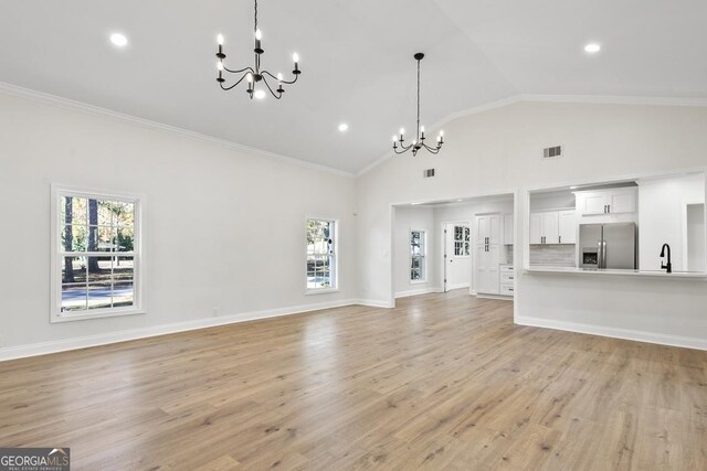 unfurnished living room with light hardwood / wood-style floors, a wealth of natural light, and a chandelier