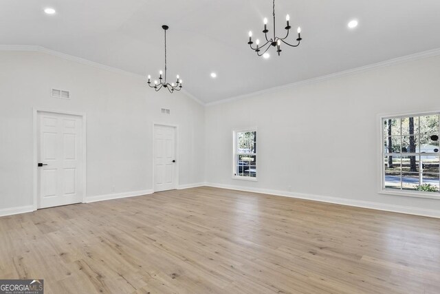 empty room with light hardwood / wood-style flooring, an inviting chandelier, plenty of natural light, and crown molding