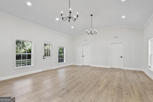 unfurnished living room with high vaulted ceiling, ornamental molding, light wood-type flooring, and a notable chandelier